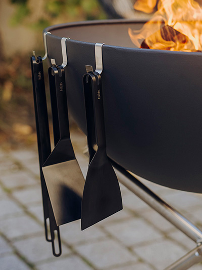 Szene zeigt einen Feuerplatz, auf dem das Bowl-Haken-Set durch seine praktische Eleganz heraussticht.