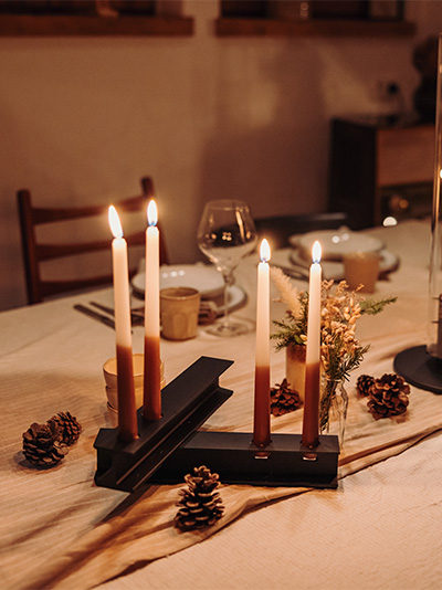 Een tafel met een kaars en een kaarsenhouder, waarop de Henry Metal Candleholder Black te zien is.