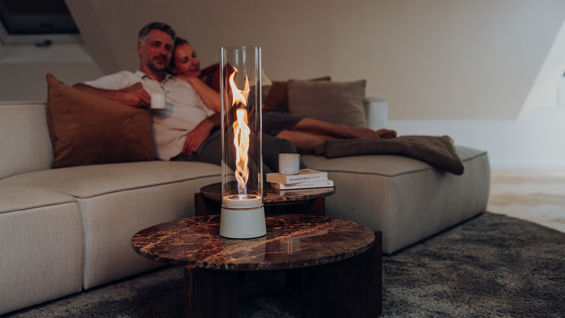 SPIN air steht auf einem Couchtisch. Im Hintergrund ein Paar gemütlich auf der Couch sitzend.