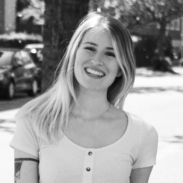 Eine Frau mit Tätowierungen steht vor einem Gebäude.