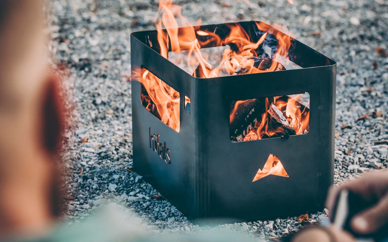 The Beer Box Firebasket is shown as a person sitting in front of a fire pit, creating a stylish and accessible visual.