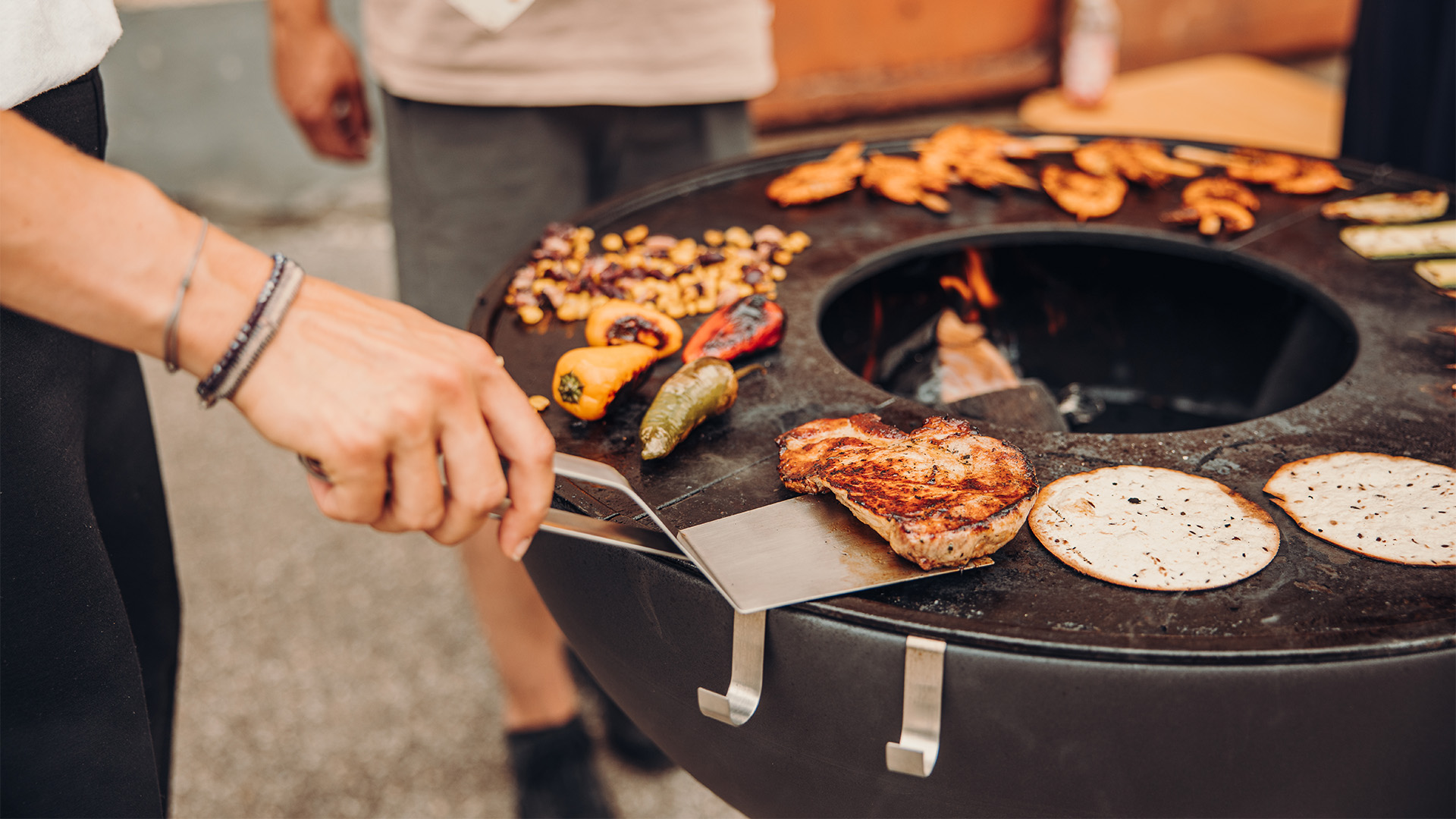 Der 00473 Spatel wird gezeigt, während eine Person Essen auf einem Grill zubereitet, was ein stilvolles und ansprechendes Bild ergibt.