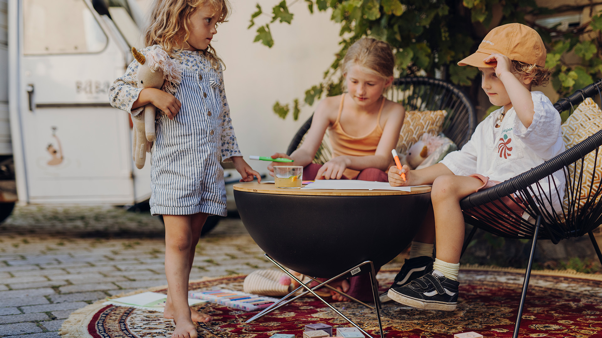 Thre little kids sitting on a chair and writing, enriched by the presence of the 00569 BOWL 57 , which serves them as a table