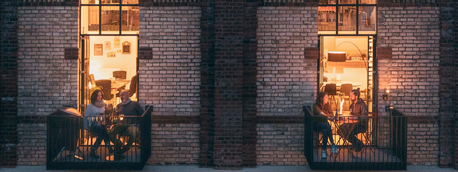 La photo montre des gens assis sur le balcon d'un immeuble la nuit, avec la cheminée de table logo SPIN.