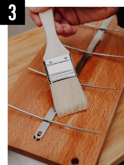 a person using a brush to paint a wooden block.