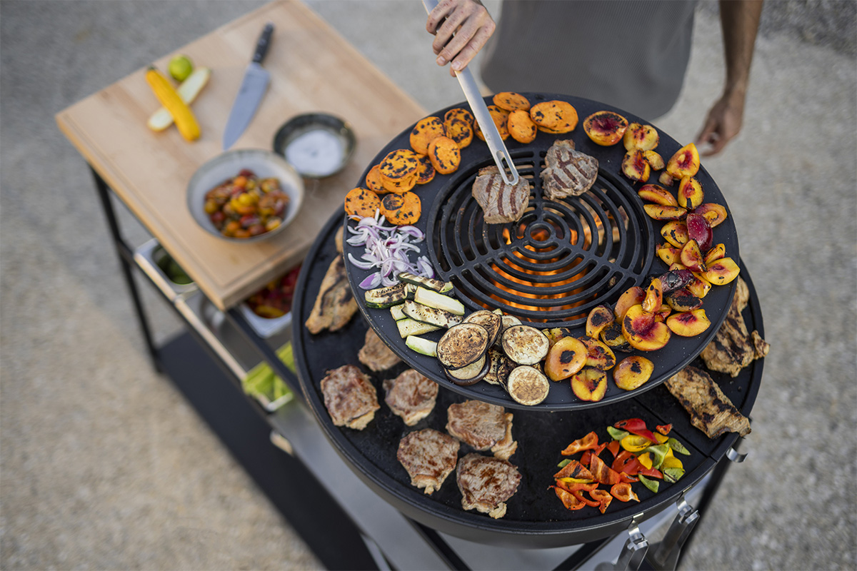 FIRE KITCHEN mit BOWL 70 Plancha-Grillset tief Erleben Sie, wie eine Person mit einem Messer den Grill vorbereitet, mit dem raffinierten Touch des 00740 Fire Kitchen Bowl 70 Plancha BBQ Sets.