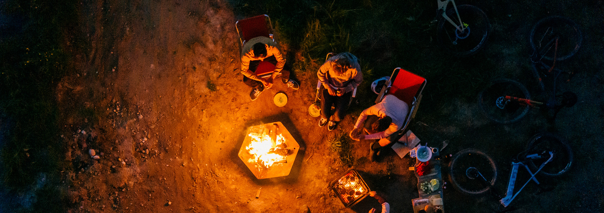 a group of people sitting around a fire.