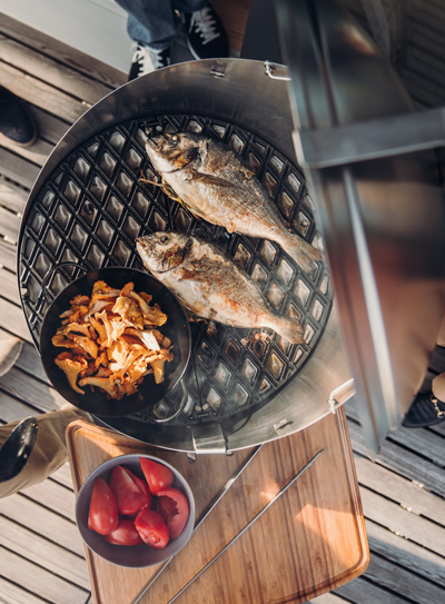 This image shows a person cooking fish on a grill, with the CONE Board.