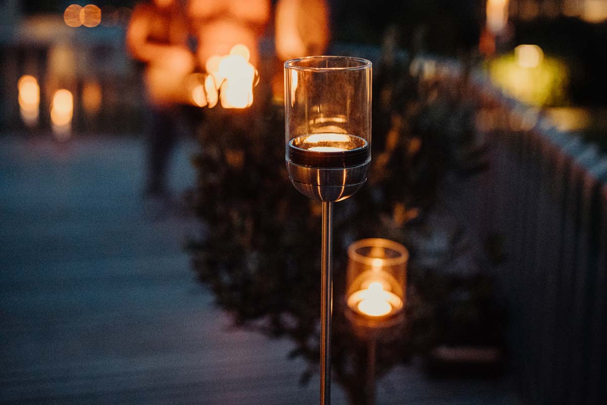 GRAVITY CANDLE Base Erleben Sie eine Kerze, die auf einem Holztisch mit dem raffinierten Touch der Gravity Candle leuchtet.