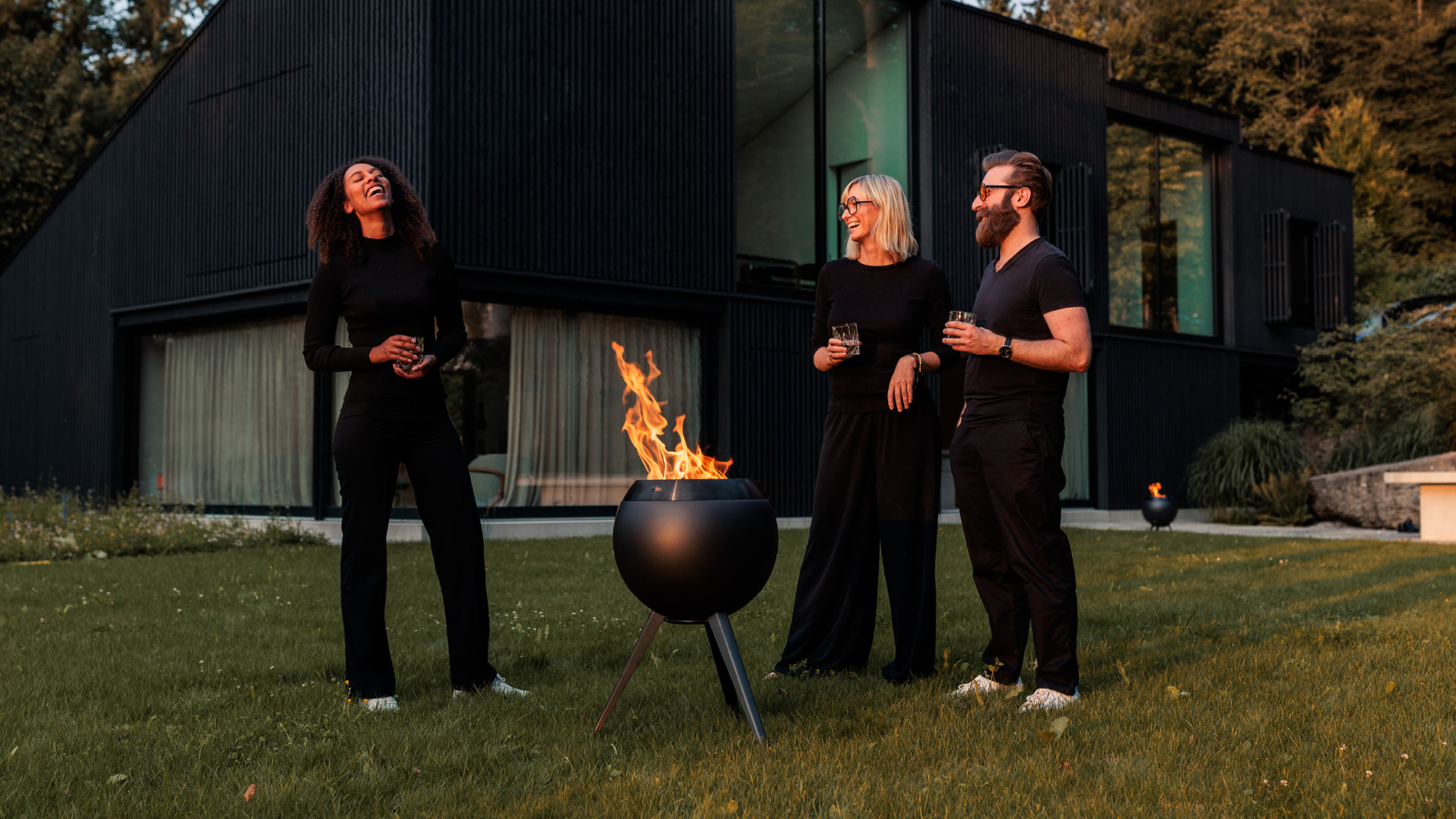 Drei schwarz gekleidete Personen stehen um die MOON black und lachen.