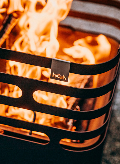 Ein Feuerplatz mit Feuer darin, der Cube in Schwarz ergänzt den Moment mit seinem durchdachten Design.