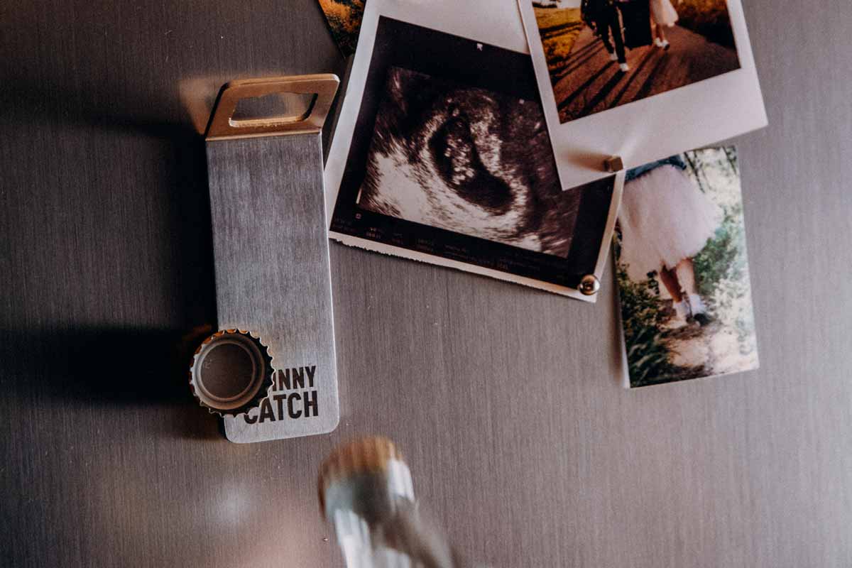 JOHNNY CATCH Magnet Bottle Opener silver This image shows a table with a bunch of polaroids on it, with the JOHNNY CATCH Magnet.
