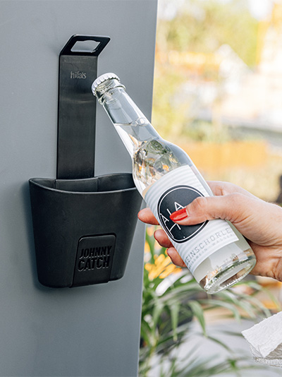 Szene, in der eine Person eine Flasche Wasser aus einem Kühler öffnet, wobei der Johnny Catch Cup Flaschenöffner durch seine praktische Eleganz hervorsticht.