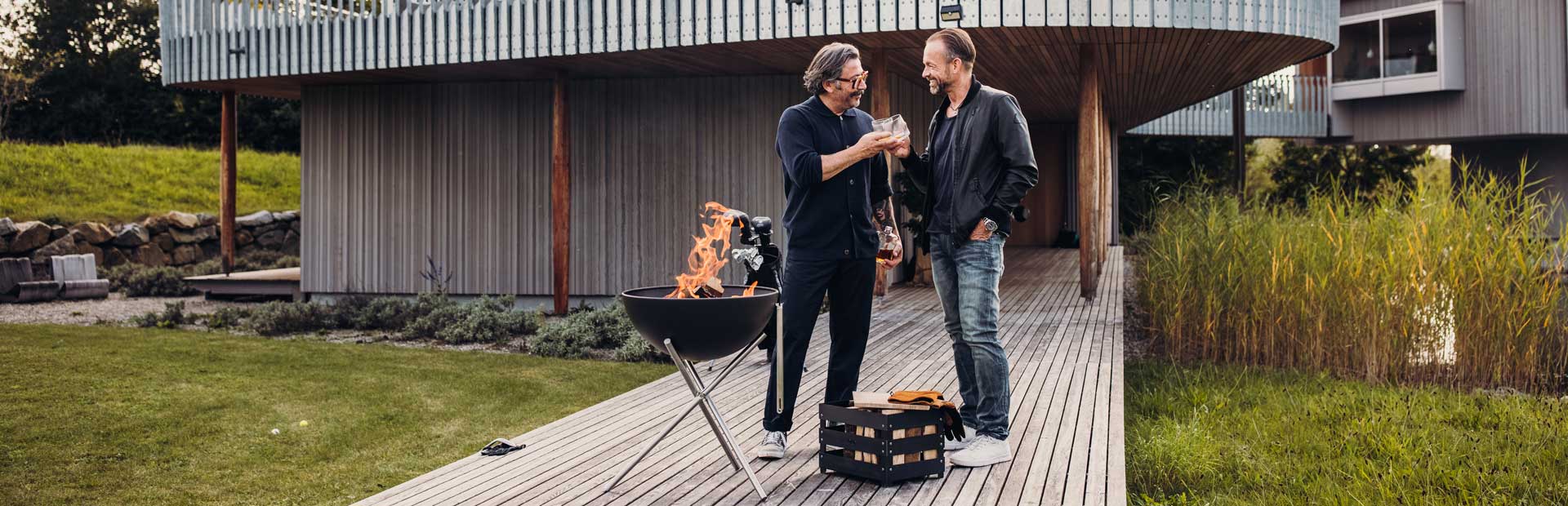 Two men standing on a deck with a barbecue, enriched by the presence Bowl, which merges design with utility.