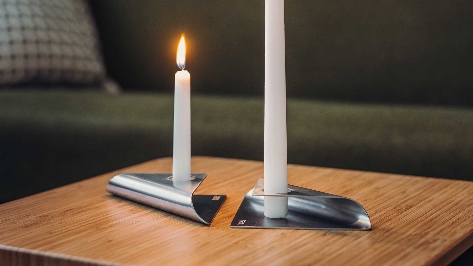 La photo présente une bougie blanche sur une table en bois, avec la SQUARE CANDLE .