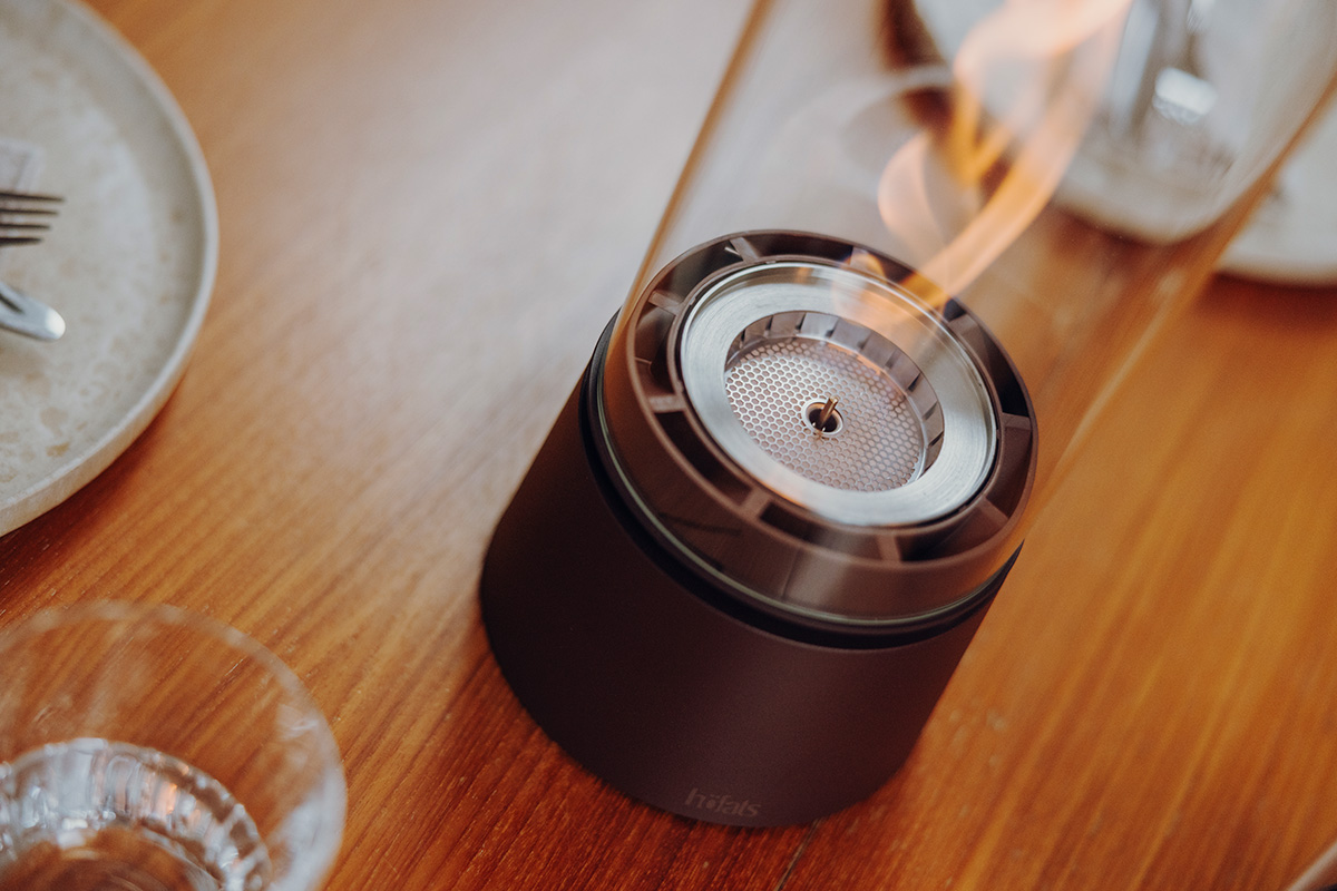 SPIN air 900 Tischfeuer rostbraun SPIN air 1200 rostbraun an einem runden Tisch mit Tellern und Menschen Close-Up