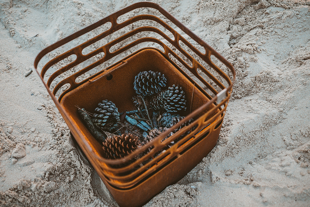 A cube firebasket filled with pinecones as a natural fueling material