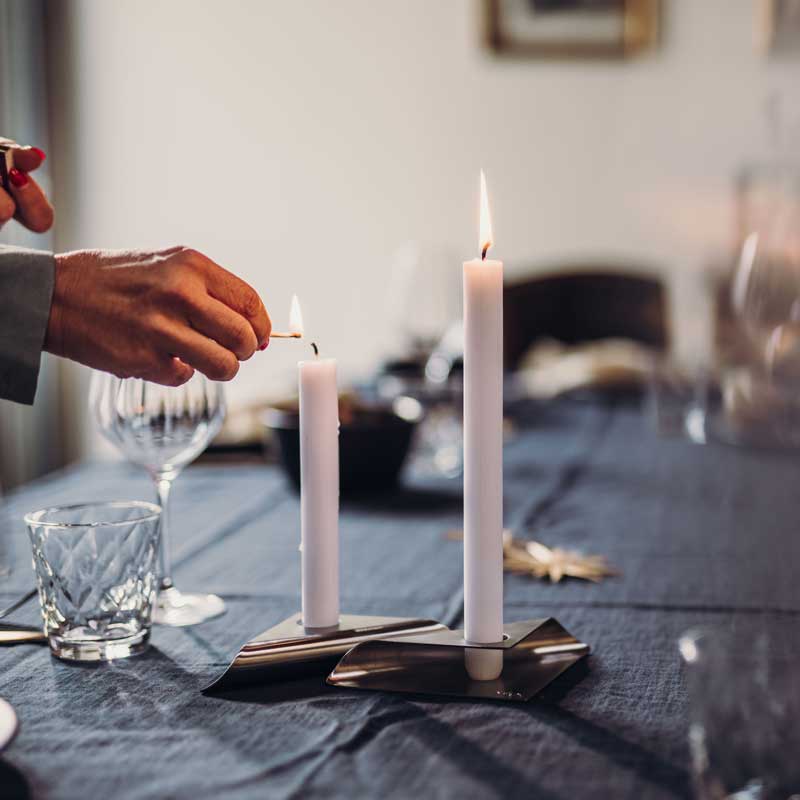 Ervaar een man die een kaars aansteekt aan een tafel met de verfijnde touch van de Square Candle Candleholder.