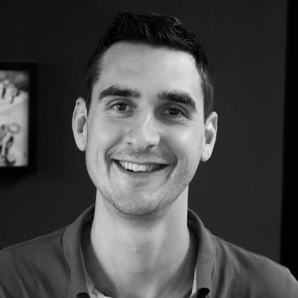 Ein lächelnder Mann auf einem schwarz-weiß Foto.