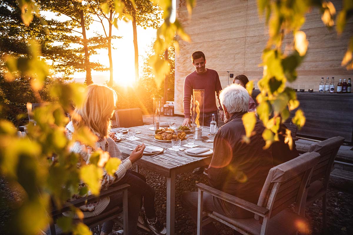 SPIN 120 Tabletop Fireplace silver Scene showing a group of people sitting around a table, where the Spin 90 Tablefire silver stands out for its practical elegance.