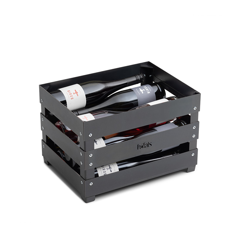 CRATE Feuerkorb Szene zeigt eine schwarze Weinkiste mit zwei Weinflaschen, wobei der Crate Firebasket durch seine praktische Eleganz hervorsticht.