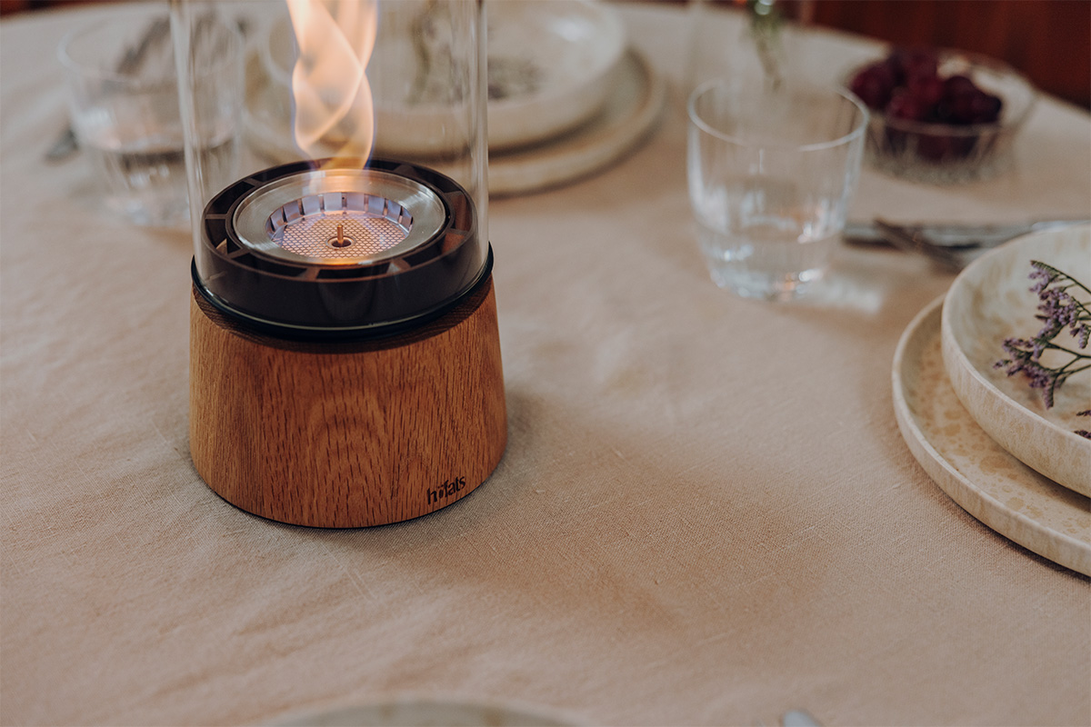 SPIN air 1200 Tischfeuer Eiche SPIN air 1200 Tischfeuer Eiche an einem runden gedeckten Tisch close-up von der Base