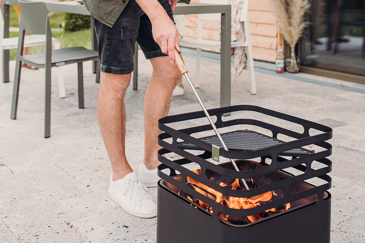 Fire Tools Set 3 pcs A man is cooking on a grill outside the 00251 Fire Tools Set 3 pcs complements the moment with its thoughtful design.