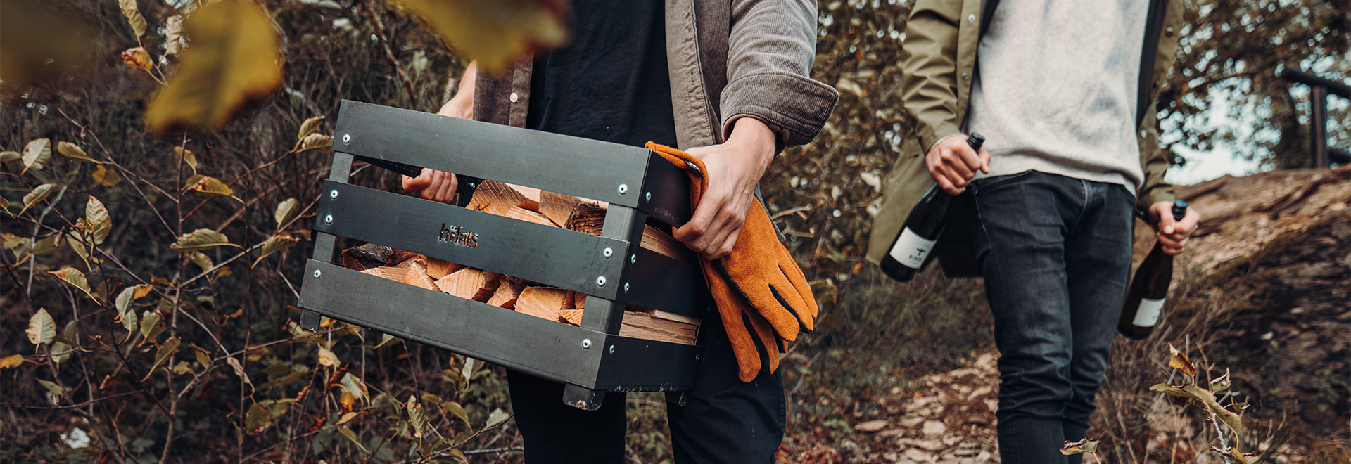 Dargestellt ist ein Mann, der einen Koffer trägt, während eine Frau hinter ihm geht, mit dem CRATE-Feuerkorb.