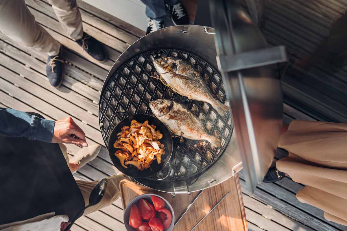 CONE Cast Iron Grid An inviting scene with a man grilling fish on a grill, highlighted by the presence of the 010301 CONE Cast Iron Grid
