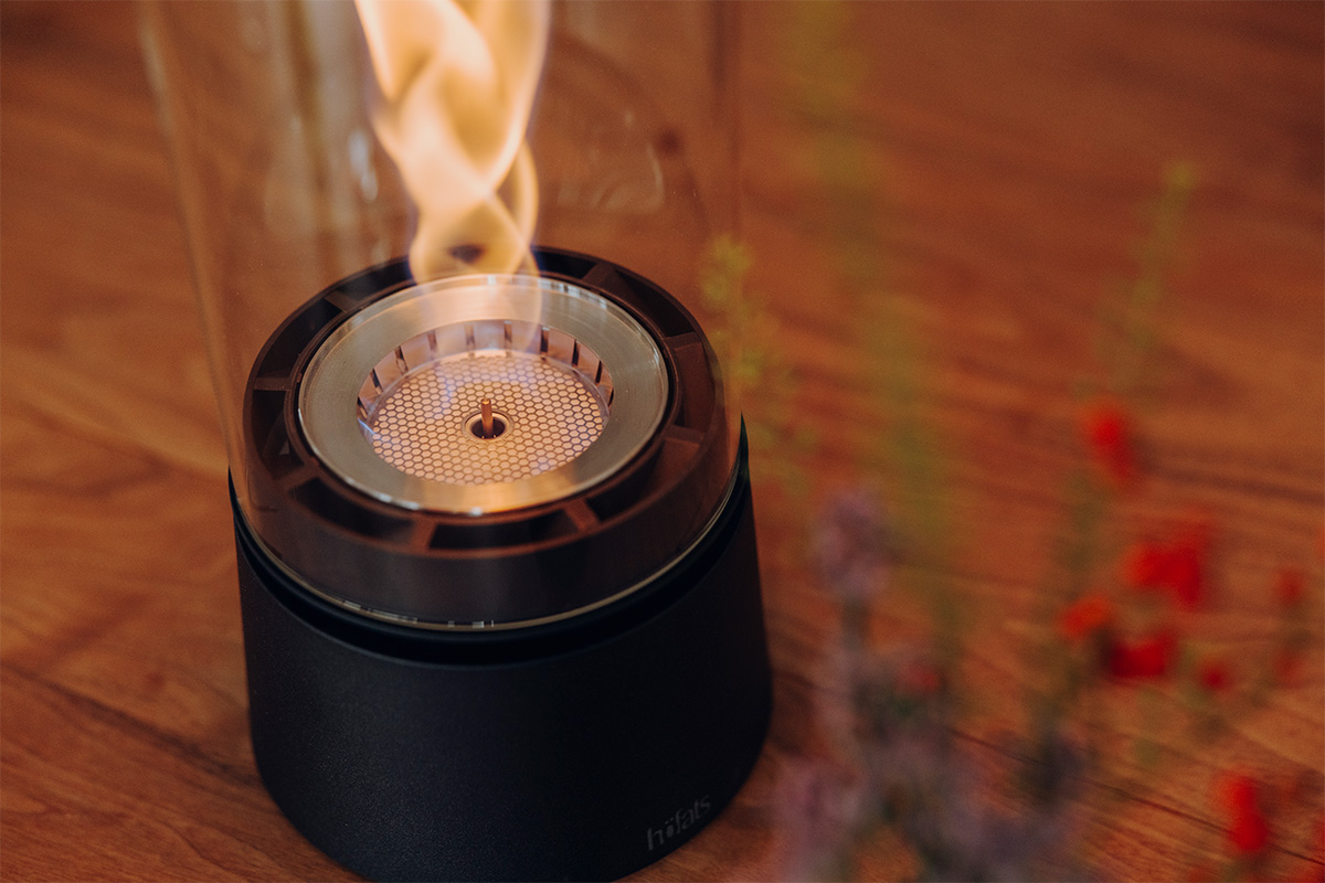 SPIN air 1200 Tischfeuer mattschwarz SPIN air 1200 und 900 mattschwarz auf einem Küchentisch mit vier Personen welche mit einem Rotwein anstoßen close-up