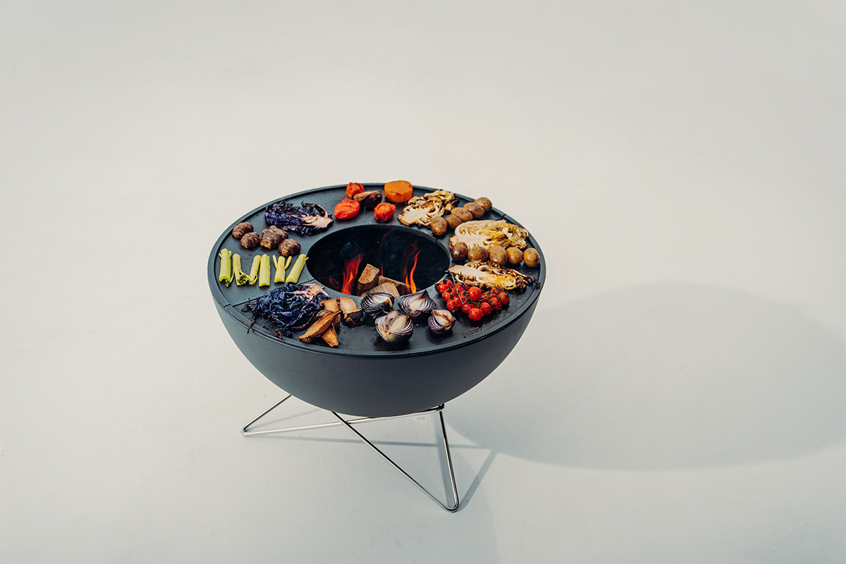 The Bowl 70 BBQ Set low integrates seamlessly into the setting, with a black bowl with planchas and grilled vegetables