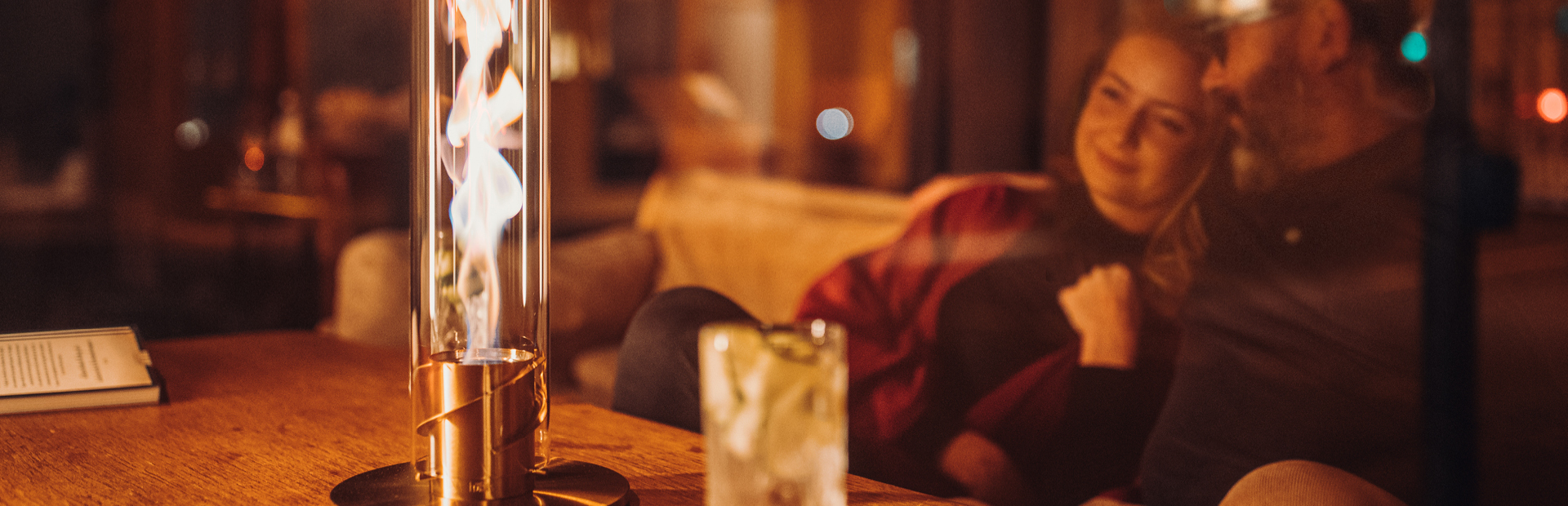 A man sitting at a table with a woman, enjoying the warmth of the SPIN Tablefire