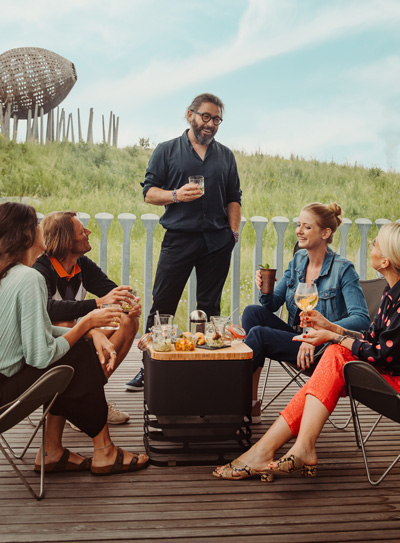 De Cube vuurkorf integreert naadloos in de omgeving, waar een groep mensen bij een vuurkorf zit.