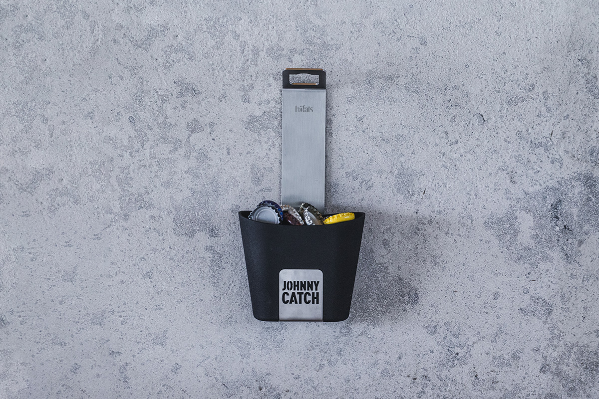 JOHNNY CATCH Cup Flaschenöffner silber Dieses Bild zeigt eine schwarze Tasche mit einem gelben Anhänger, an dem der JOHNNY CATCH Cup hängt.