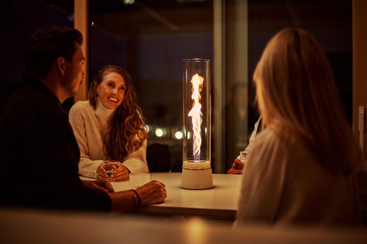 SPIN air 1200 Feu de table crème Drei Personen sitzen an einem Tisch um SPIN air 1200 creme und unterhalten sich im Licht der Flamme.