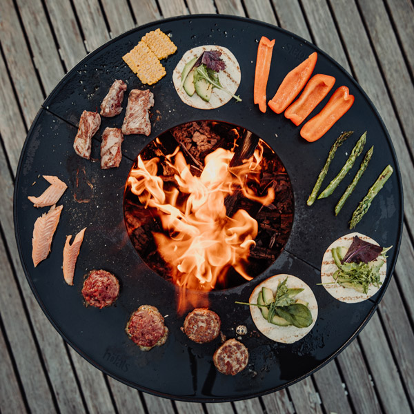 An image showing a black plate with food on it, with the BOWL Fire Bowl with Tripod.