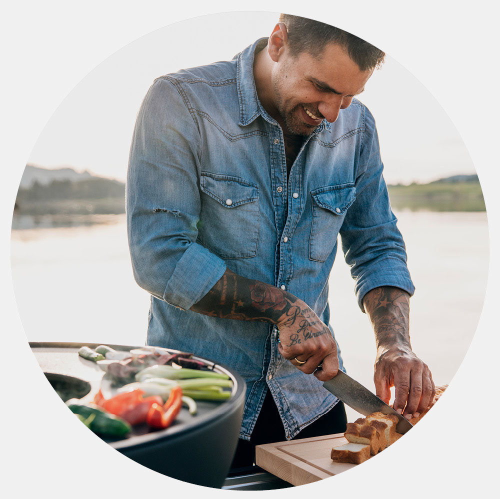 Un homme coupe une part de pizza sur une table.