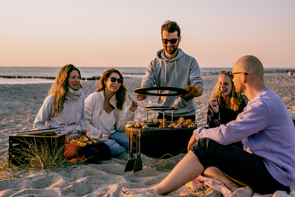 BOWL 57 Anneau Chauffant Ici est représenté un groupe de personnes assis sur une plage, avec le BOWL 57 Warming Ring.