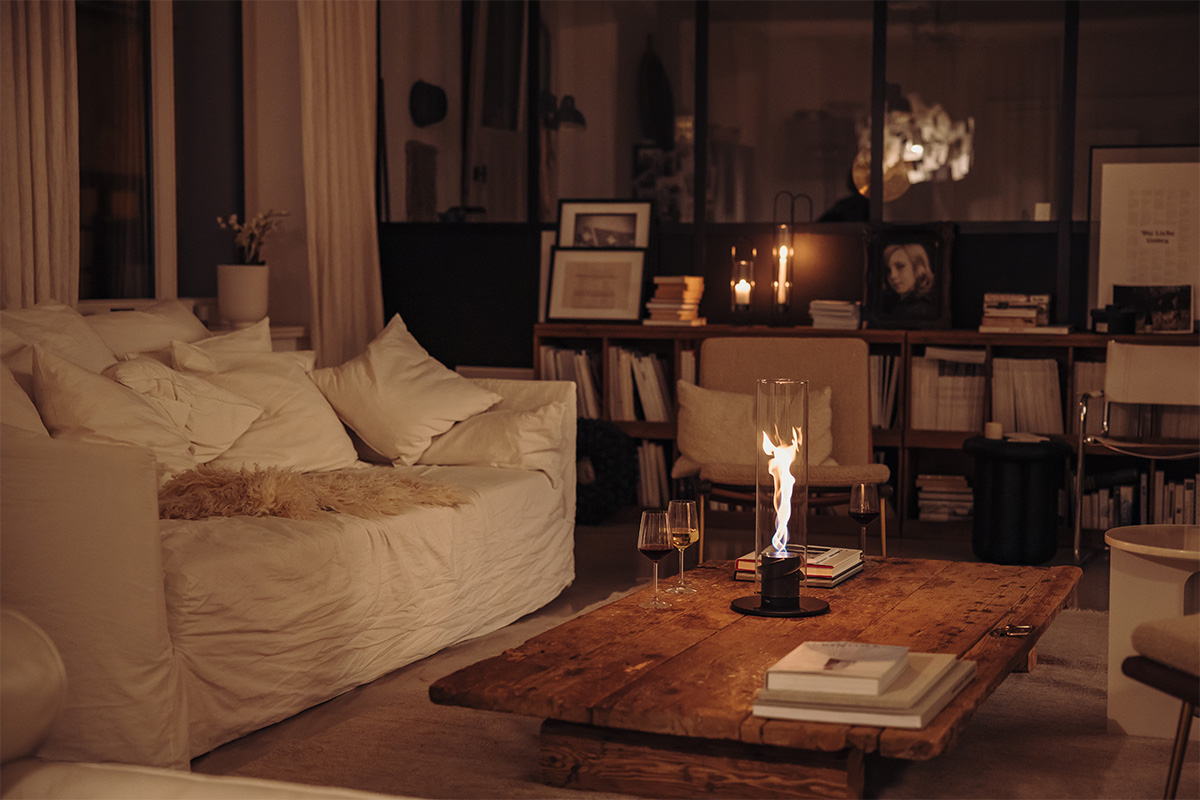 SPIN 1200 Tabletop Fireplace black A living room with a couch, coffee table, and a Tablefire. the 00700 Spin 1200 Tablefire black complements the moment with its thoughtful design.