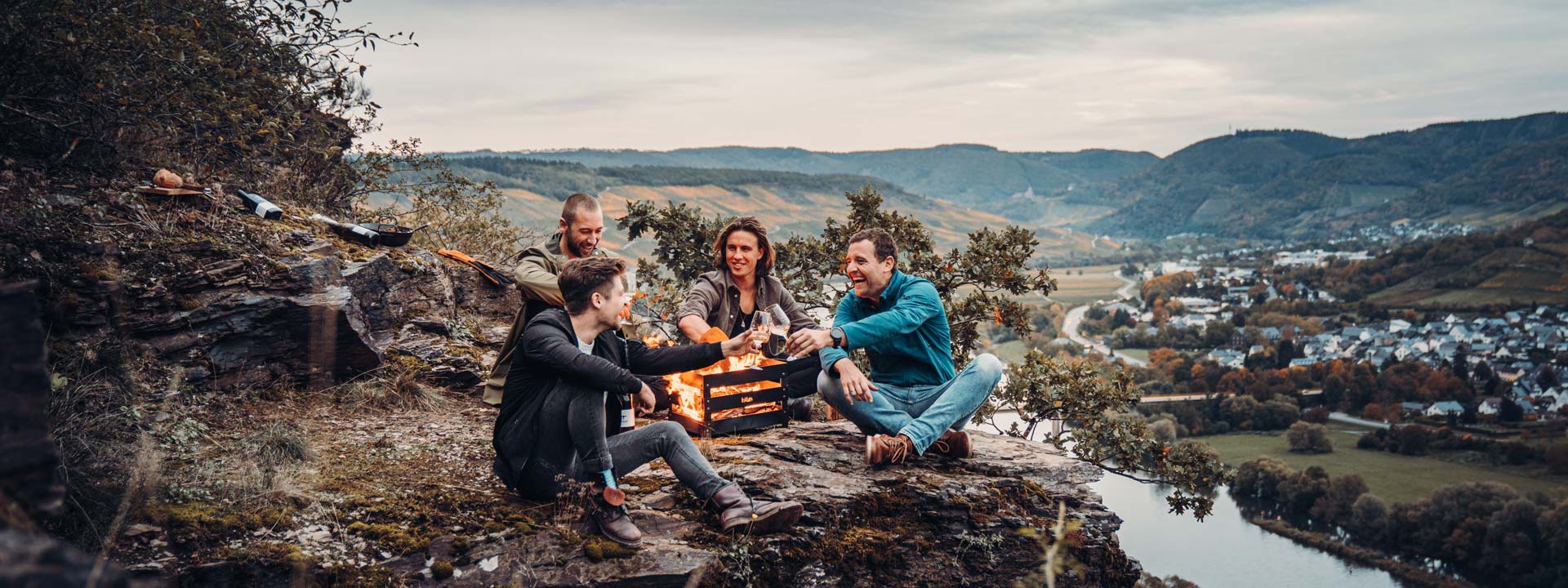 Een uitnodigende scène met twee mensen die op een rots zitten bij een kampvuur, benadrukt door de aanwezigheid van de Crate Fireplace.