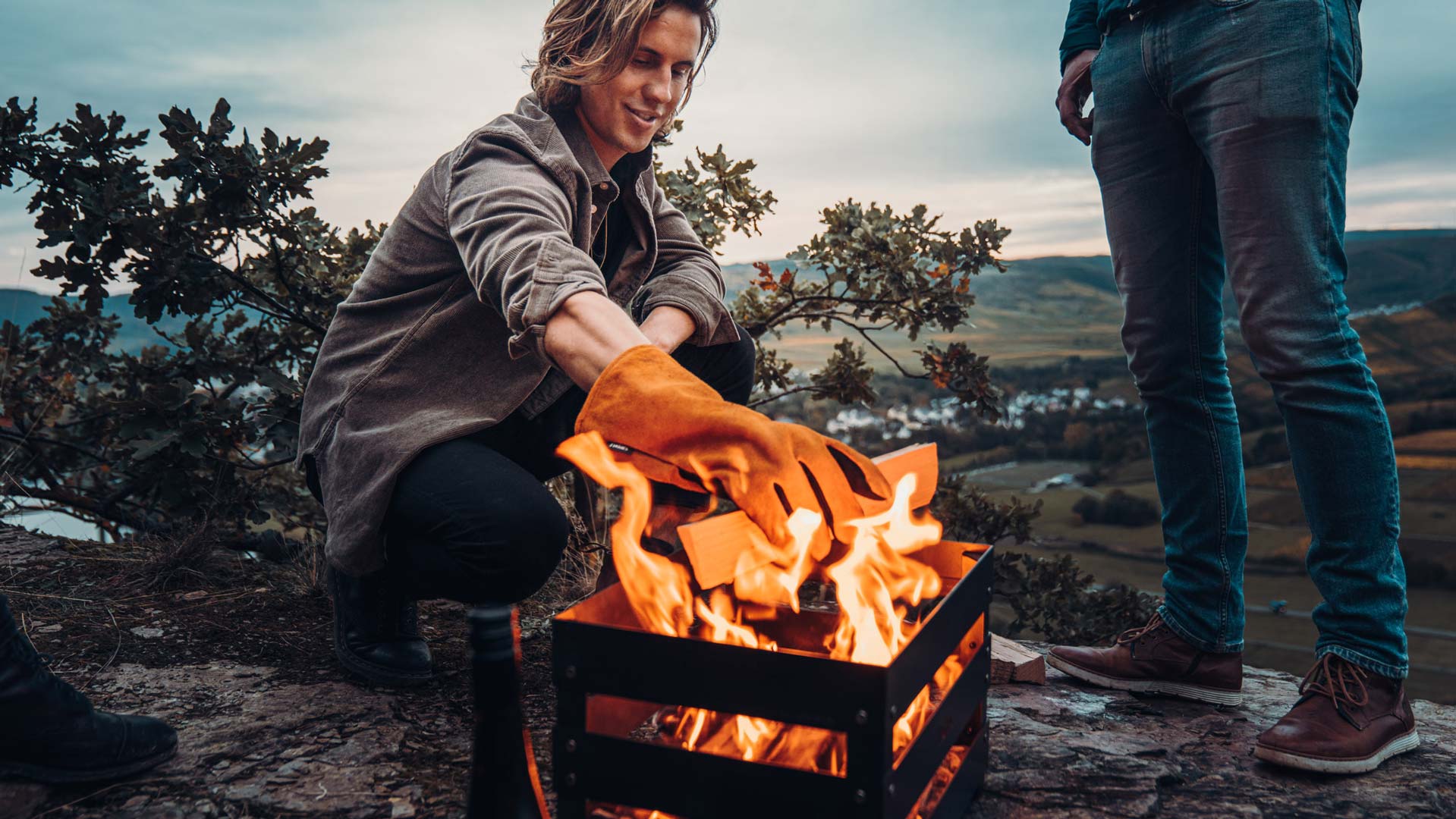 Une femme assise sur un rocher près d'un feu, enrichie par la présence des outils Glove, qui fusionnent design et utilité.