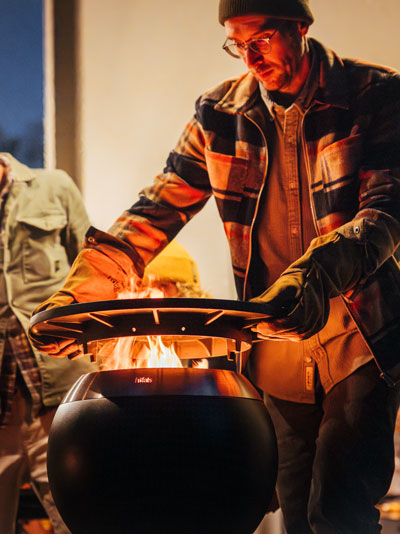A man is cooking on a large grill the MOON 45 Plancha complements the moment with its thoughtful design.