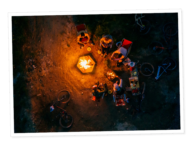 a group of people sitting around a fire.