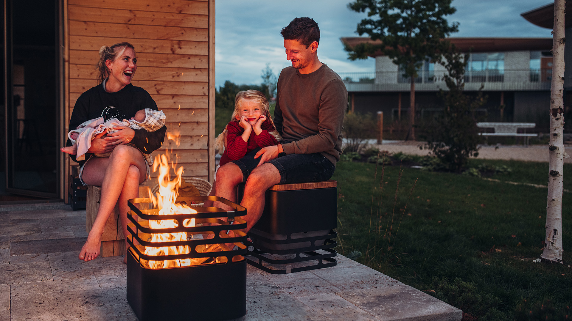 Der Cube Flip wird als Mann und Frau dargestellt, die auf einer Bank an einem Feuer sitzen und ein stilvolles und zugängliches Bild schaffen.