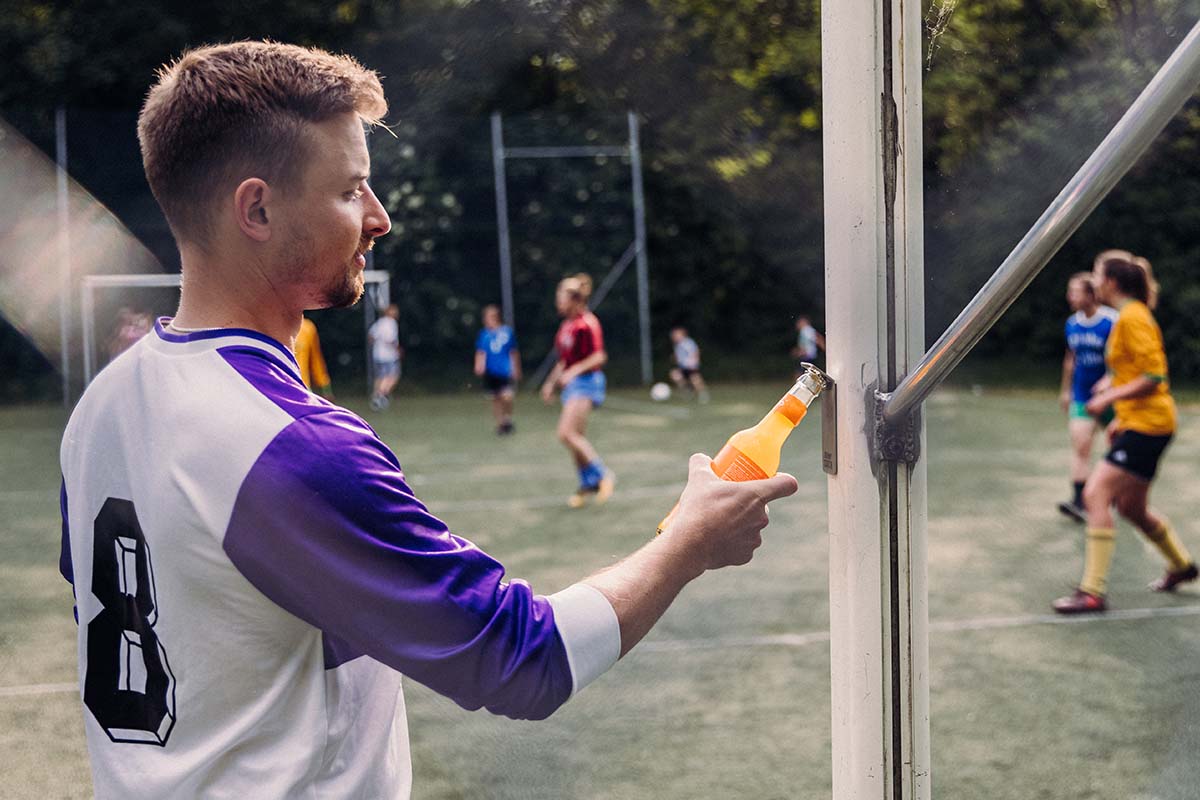 JOHNNY CATCH Magnet Bottle Opener silver A man holding an orange drink openin the bottle. the Johnny Catch Magnet Bottleopener complements the moment with its thoughtful design.